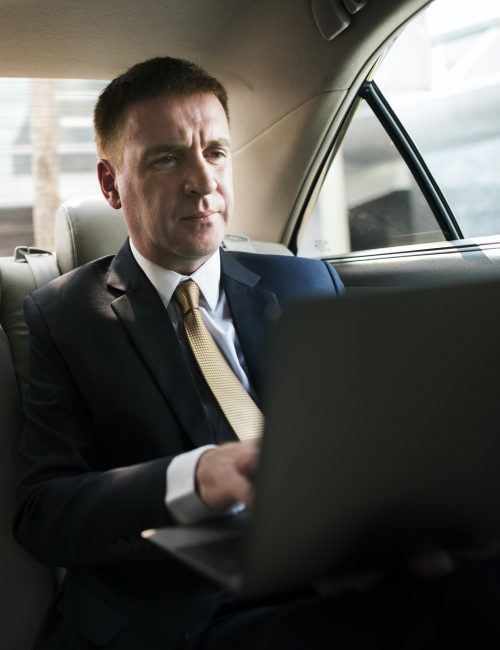 Businessman inside a car working on his laptop