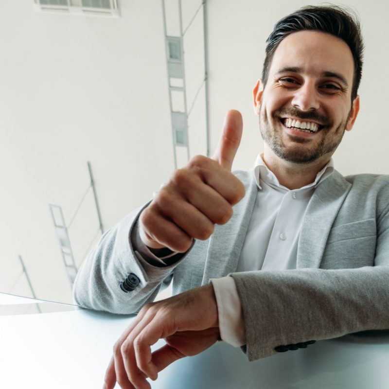 Happy business man shows thumb up sign gesture